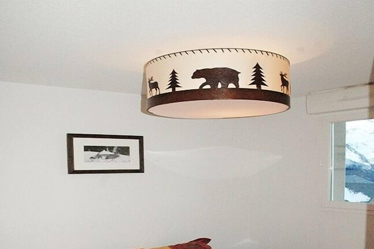 Een slaapkamer met een bed, een lamp, een ingelijst kunstwerk en een raam.