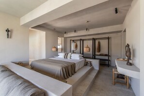 Un dormitorio moderno con una cama grande, una mesita de noche, una silla y un escritorio pequeño con una lámpara.
