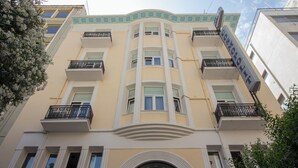 Un hôtel à plusieurs étages, doté de balcons, d’une arche centrale et d’une enseigne indiquant qu’il s’agit d’un hôtel.