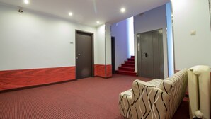 Un hall d’hôtel avec un tapis rouge, un canapé et un escalier.