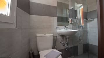 A modern bathroom with a toilet, sink, and glass-enclosed shower.