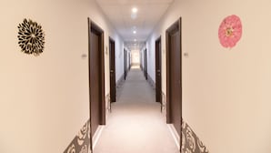 Un couloir d’hôtel avec des portes numérotées 210 et 211, une moquette à motifs et des œuvres d’art décoratives accrochées aux murs.