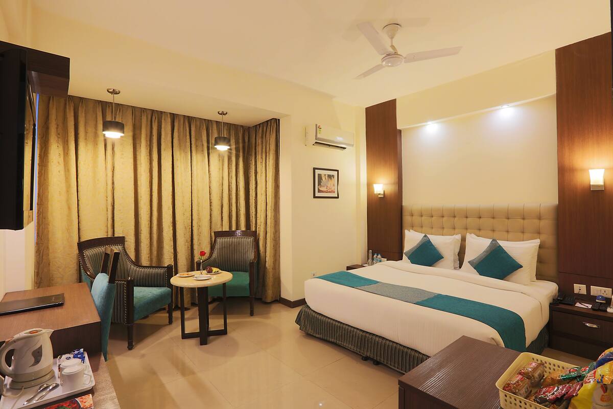 A hotel room with a bed, a desk, a chair, a table, and a ceiling fan.