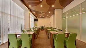 A conference room with multiple tables and chairs, large windows, and a wooden ceiling. - Whiz Hotel Malioboro Yogyakarta (Yogyakarta)