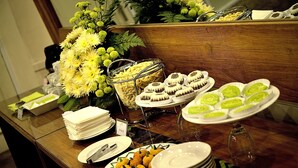 A buffet table with various food items, including pastries and a fruit bowl. - Whiz Hotel Malioboro Yogyakarta (Yogyakarta)