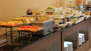 Ein Buffet mit verschiedenen Speisen, darunter Obst, Sandwiches und Getränke.