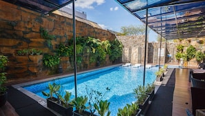 Ein Pool mit Steinwänden und Topfpflanzen.