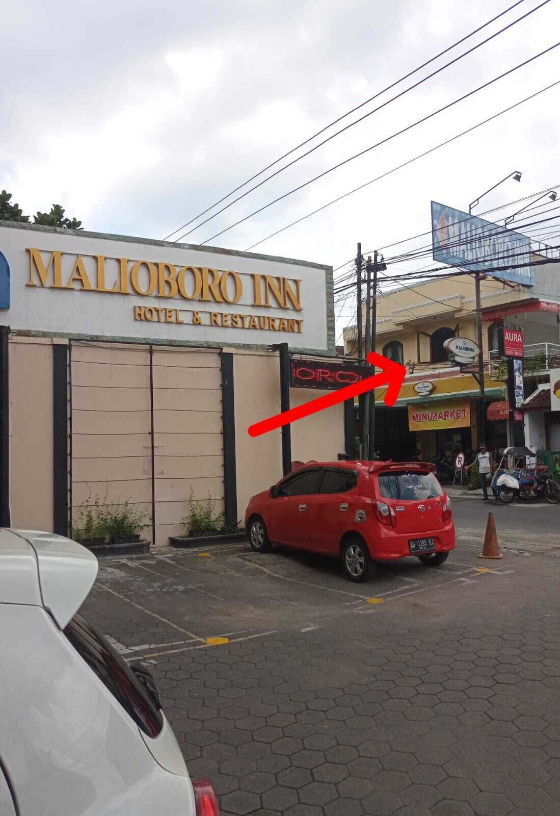A MALIBORO INN HOTEL & RESTAURANT with a red car parked in front.