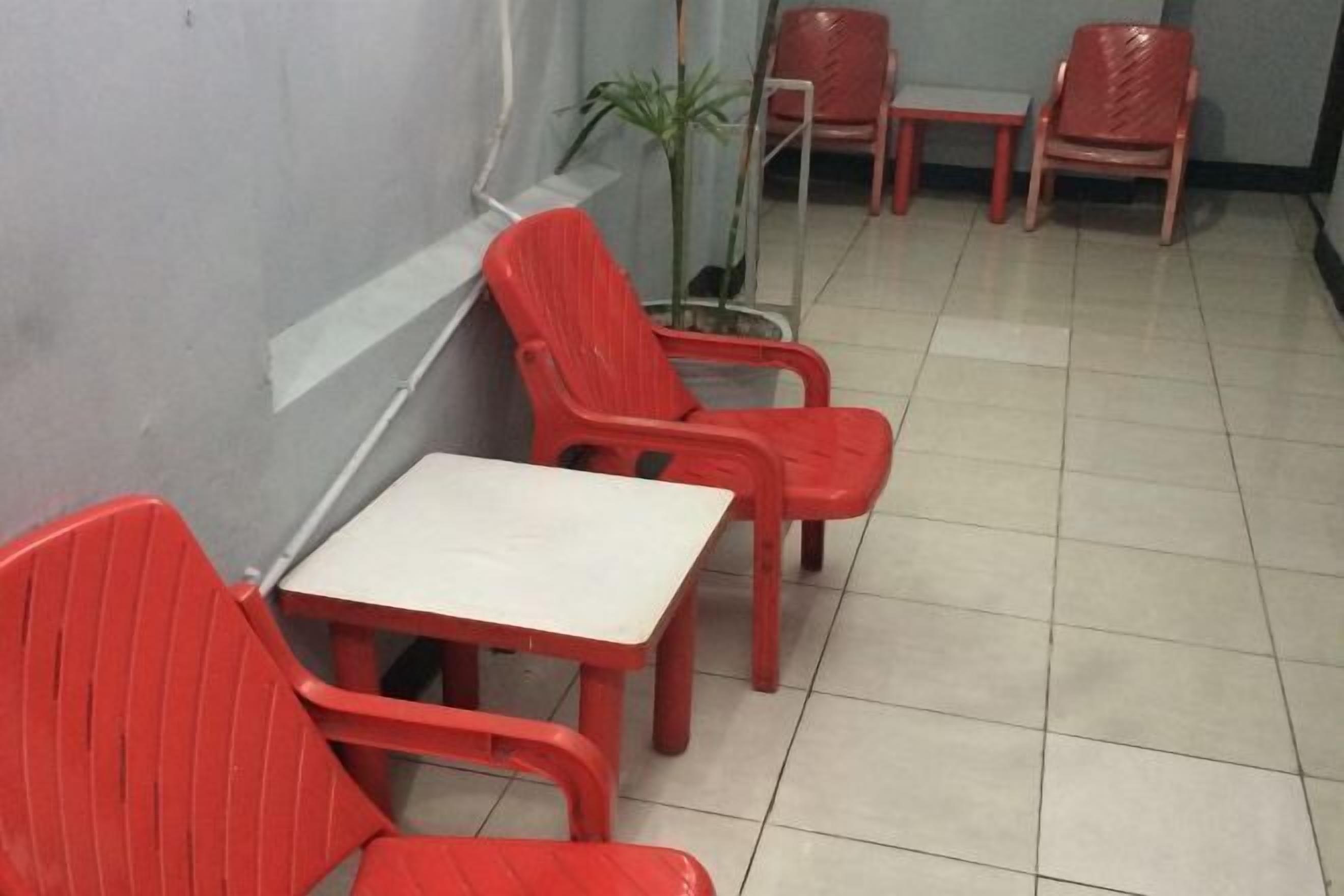 A small room with a white table and four red chairs.