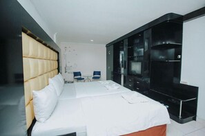 A modern hotel room with a large bed, a flat-screen TV, and a black entertainment unit. - New Hotel Lilik (Yogyakarta)