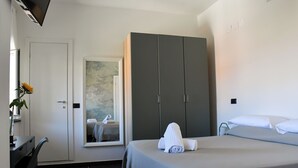 Habitación de hotel con cama, escritorio, armario y ventana con vistas.