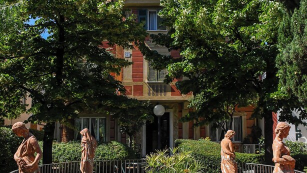 Un patio con una fuente, estatuas y un edificio al fondo.