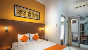 Una habitación de hotel con una cama grande, dos lámparas de noche, una obra de arte enmarcada en la pared y un banco de madera.