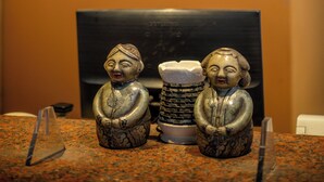 Una mesa con dos figuritas de cerámica y una pila de toallas dobladas.