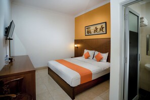 Habitación de hotel con cama, escritorio, silla, ducha y lavamanos en el baño.
