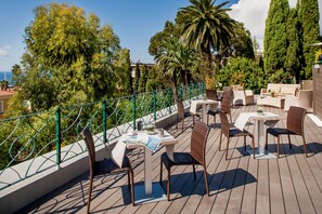 A rooftop terrace with outdoor seating, a view of the sea, and surrounding greenery. - Villa Sylva & Spa (Sanremo)