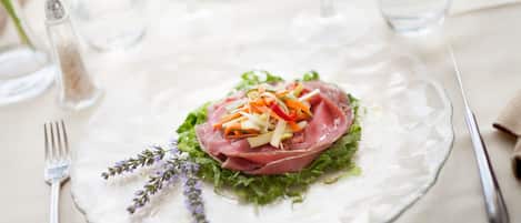 A clear glass plate with a salad on a table, accompanied by a fork and a knife.