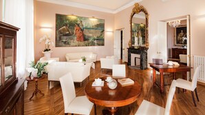 A spacious living room with a large painting, a fireplace, and a dining area with a wooden table and white chairs. - Villa Sylva & Spa (Sanremo)