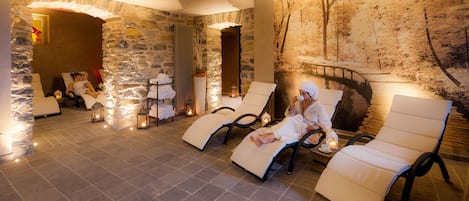 A spa area with stone walls, reclining chairs, and a mural of a winter scene.
