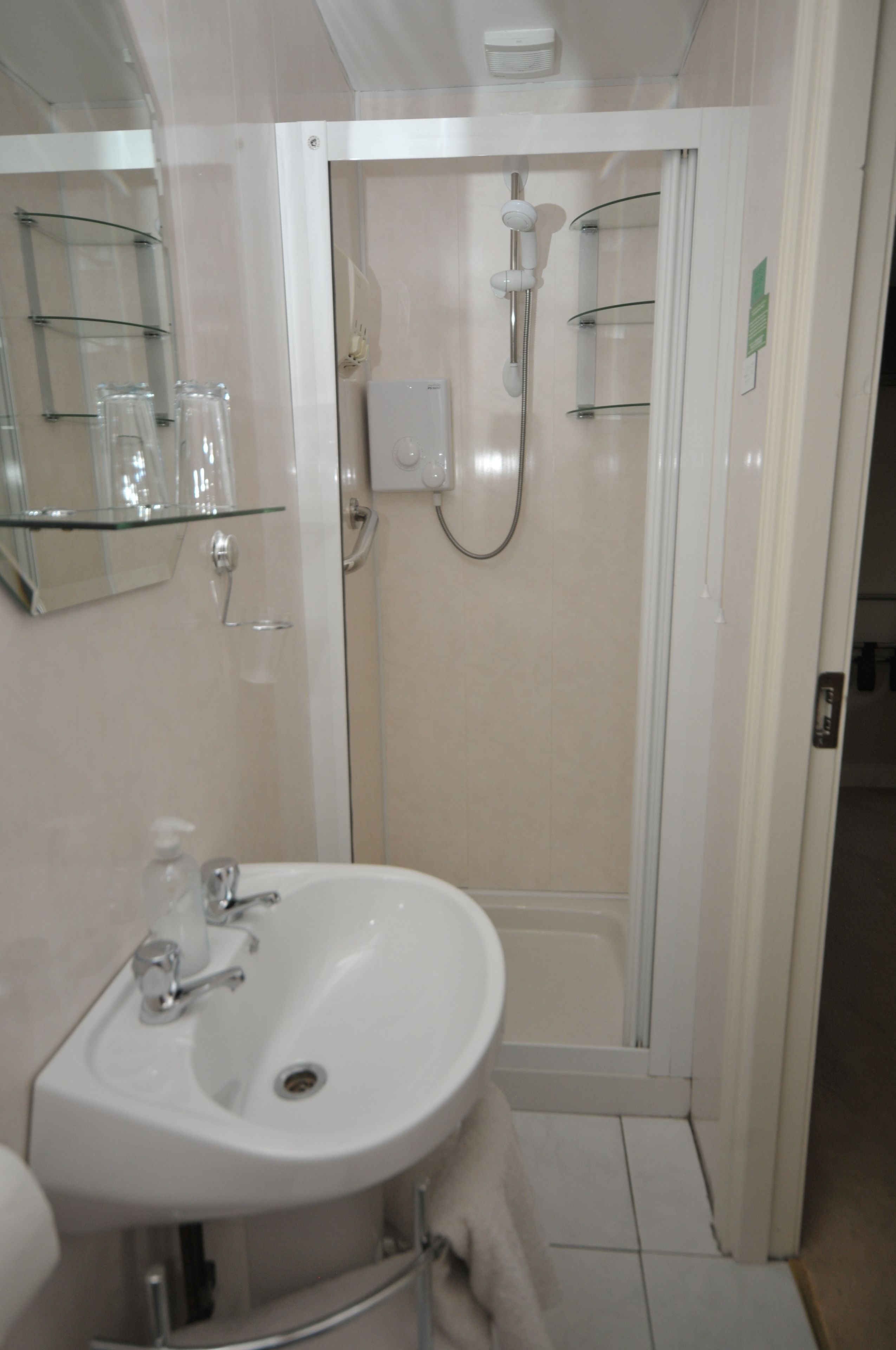 A bathroom with a sink, mirror, and shower.