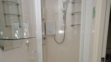 A bathroom with a sink, mirror, and shower.