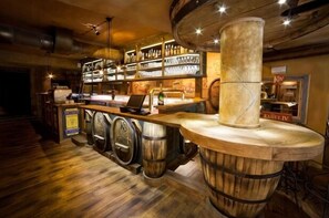A bar area with wooden barrels, shelves with bottles, and a counter with a laptop. - Apartmany Becherplatz (Karlovy Vary)