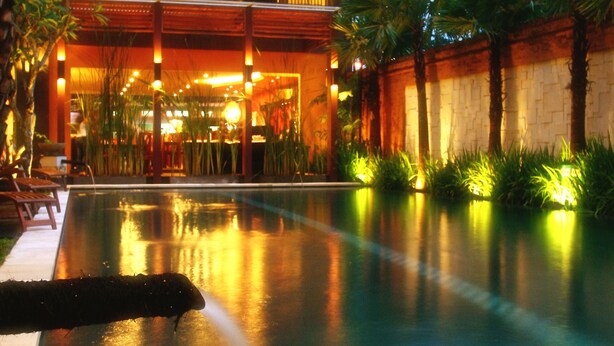 Ein Hotel mit Schwimmbad, Außenbereich zum Sitzen und einem gut beleuchteten Eingang.