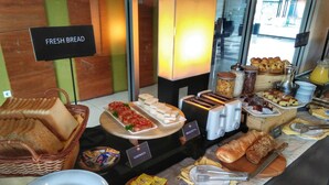 Ein Frühstücksbuffet mit frischem Brot, Sandwiches, Gebäck und Beilagen.