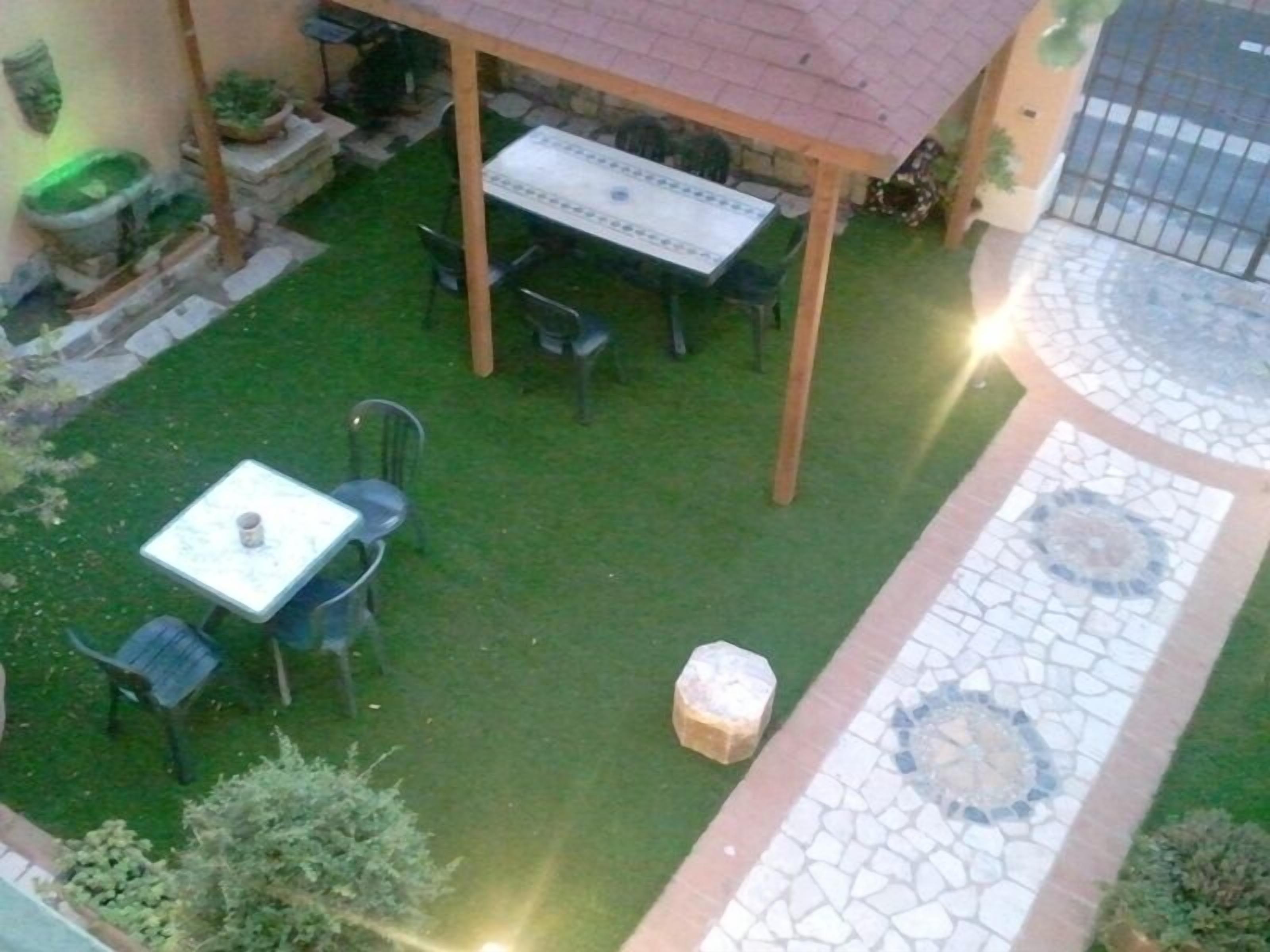 En terrasse med et bord og stole, omgivet af en lille græsplæne og en flisetrappe.