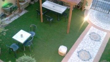 En terrasse med et bord og stole, omgivet af en lille græsplæne og en flisetrappe.
