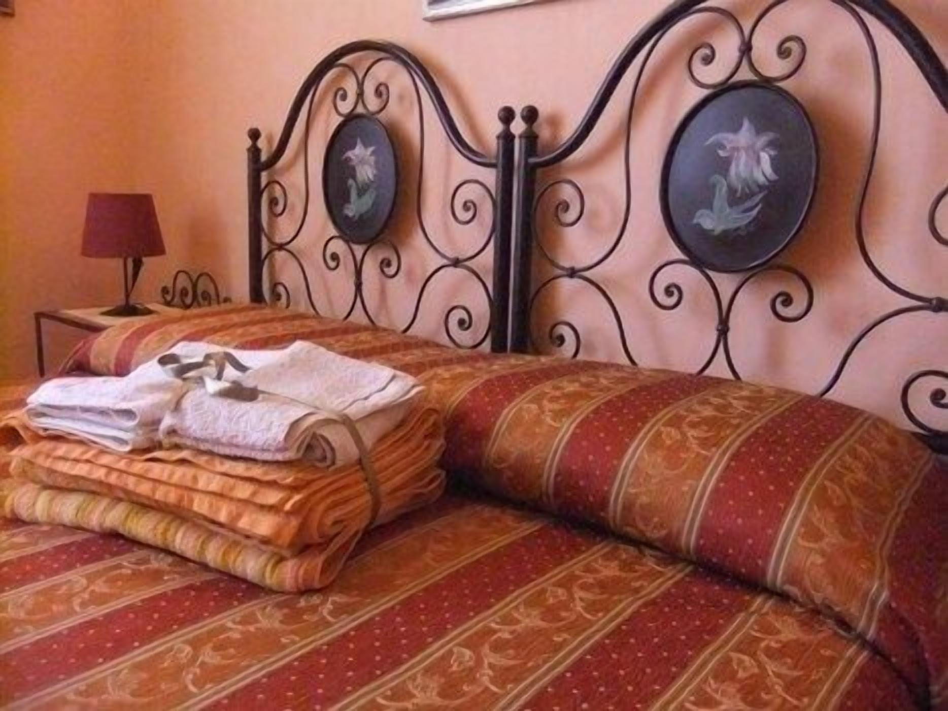Cama bem arrumada com toalhas dobradas e cabeceira decorativa com duas peças de arte circular na parede.