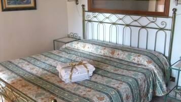 A bed with a floral bedspread, a headboard with a decorative mirror, and a wall-mounted lamp.