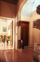 A hallway with a wooden door, a stone pillar, and a dining area with chairs and a table.