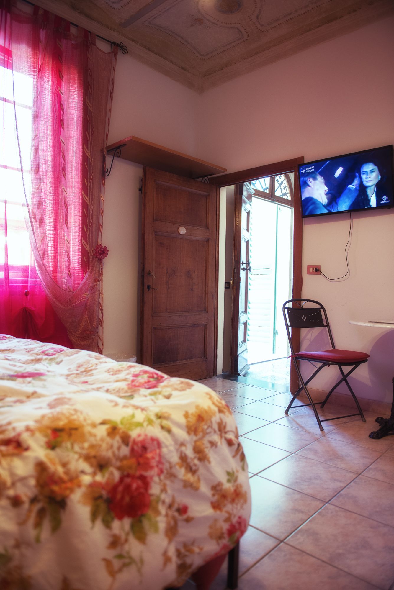 Une chambre à coucher avec un lit, une porte en bois, un téléviseur et une chaise.