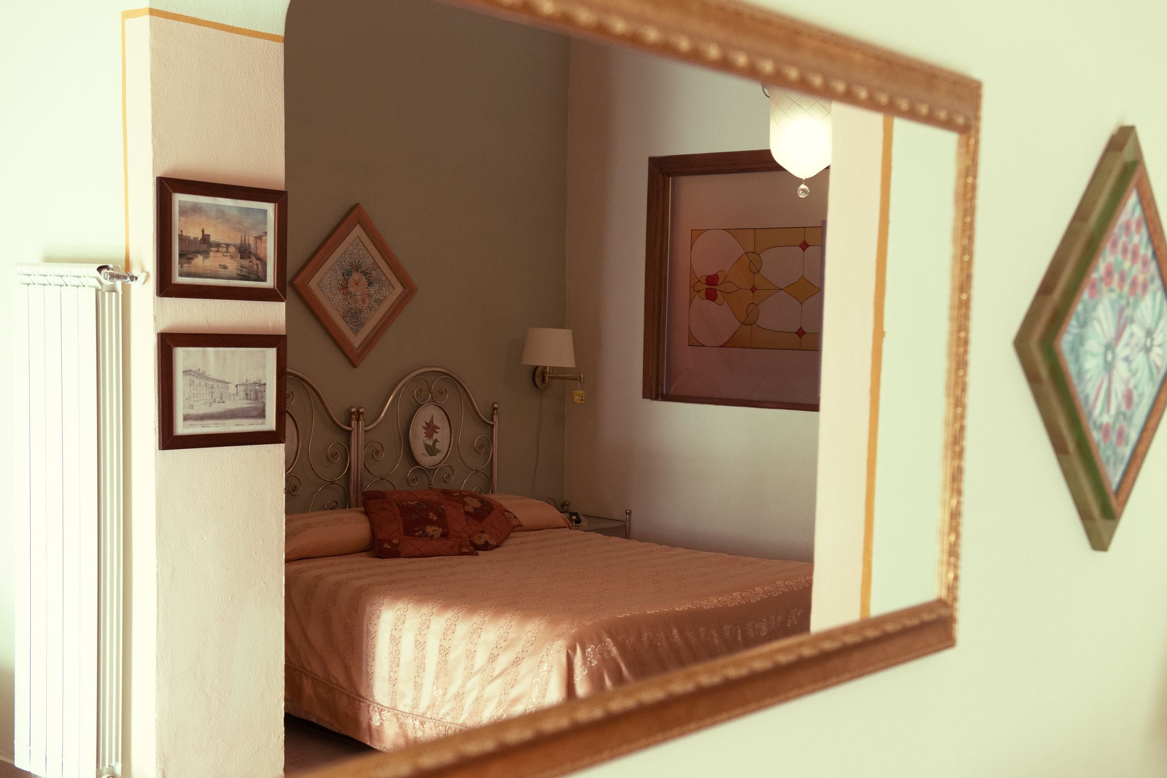 Un dormitorio con cama, mesita de noche, lámpara y cuadros en la pared.