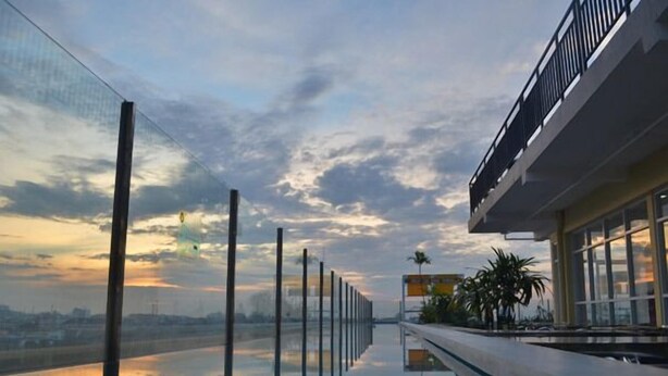 A modern building with a glass facade reflecting the sky. - EDU Hostel (Yogyakarta)