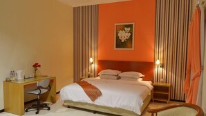 A hotel room with a bed, desk, chair, and a painting on the wall. - Hotel Kings Kudus (Kudus)