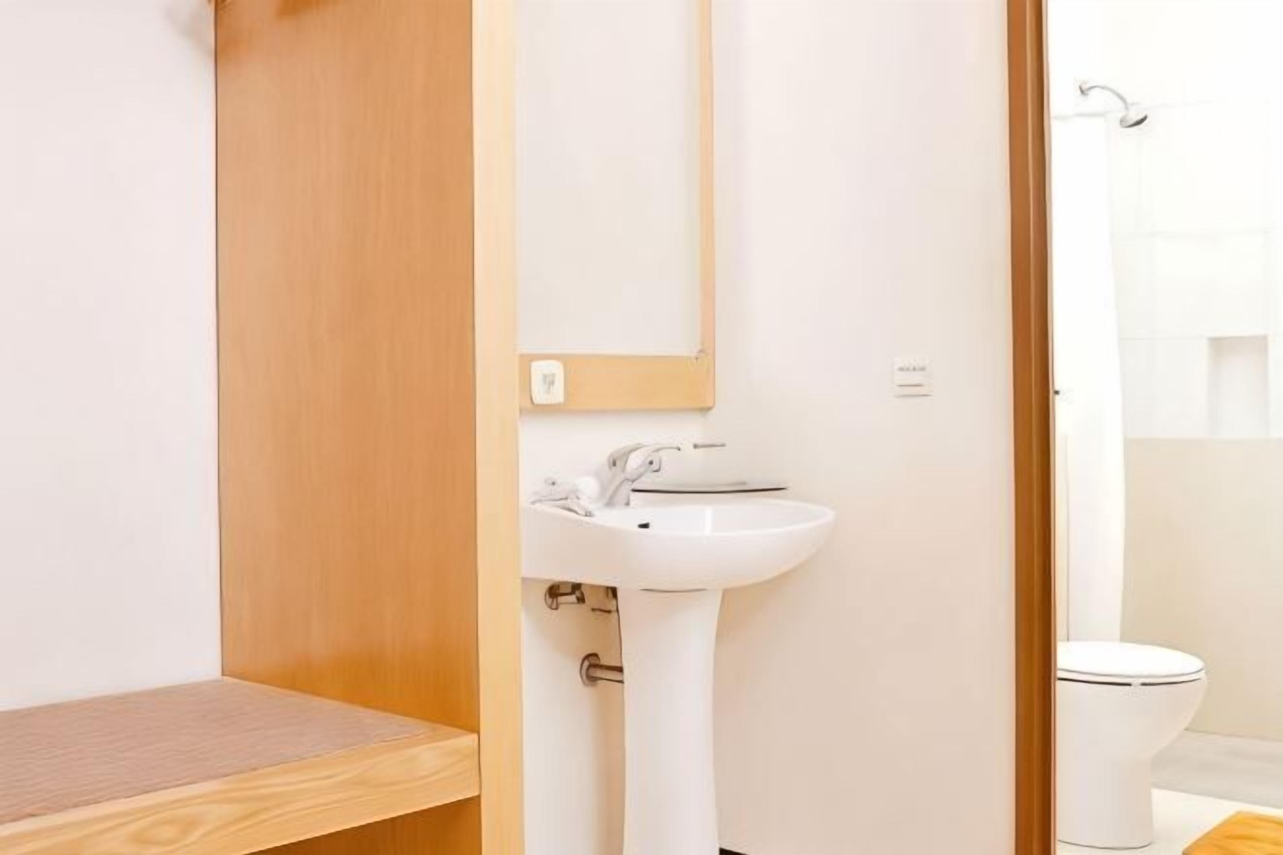 A bathroom with a wooden vanity, a white sink, and a toilet.