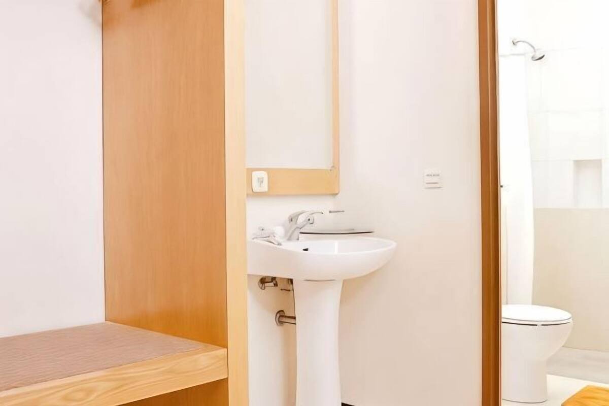 A bathroom with a wooden vanity, a white sink, and a toilet.