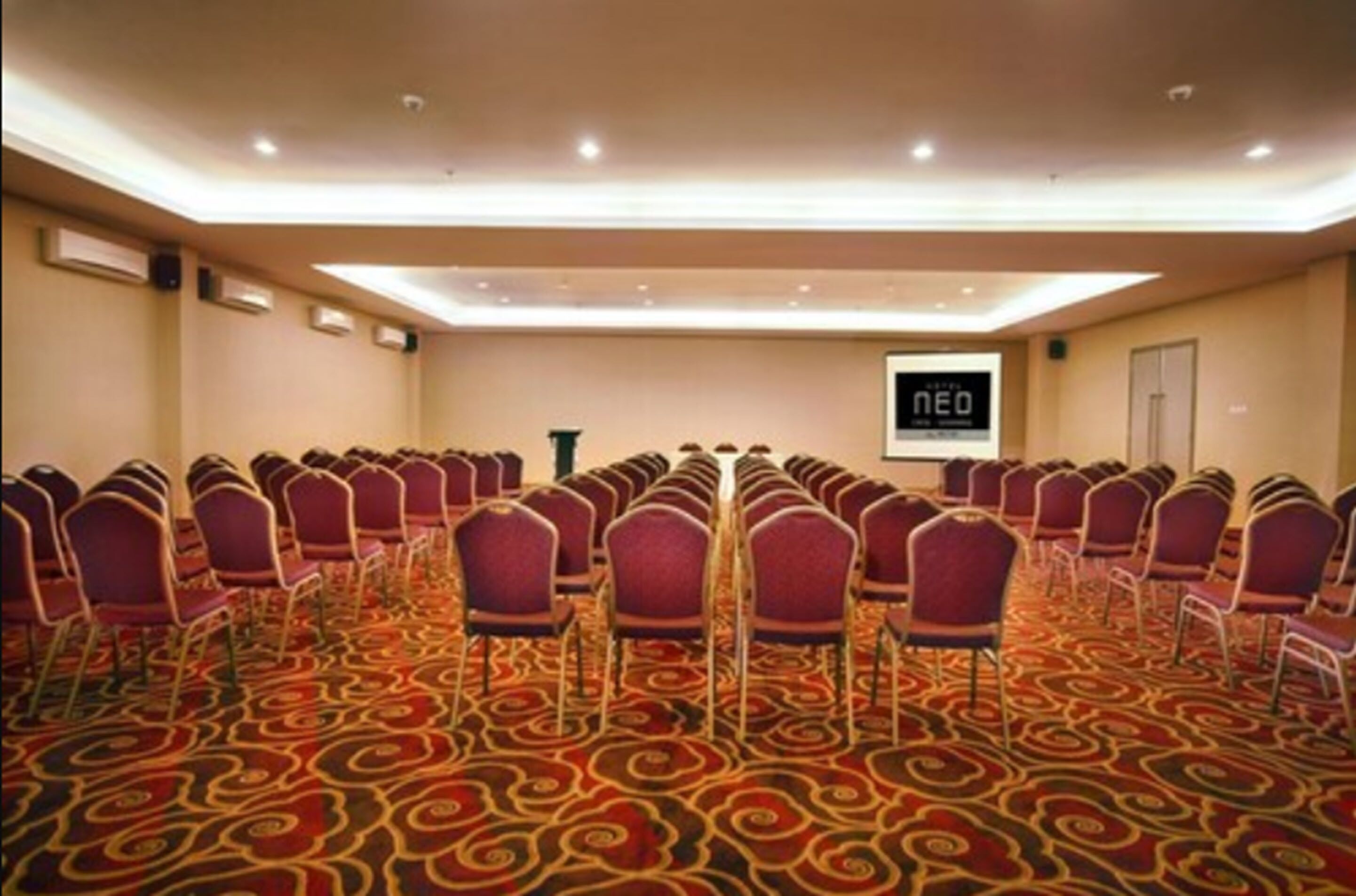 A conference room with rows of purple chairs and a carpeted floor.