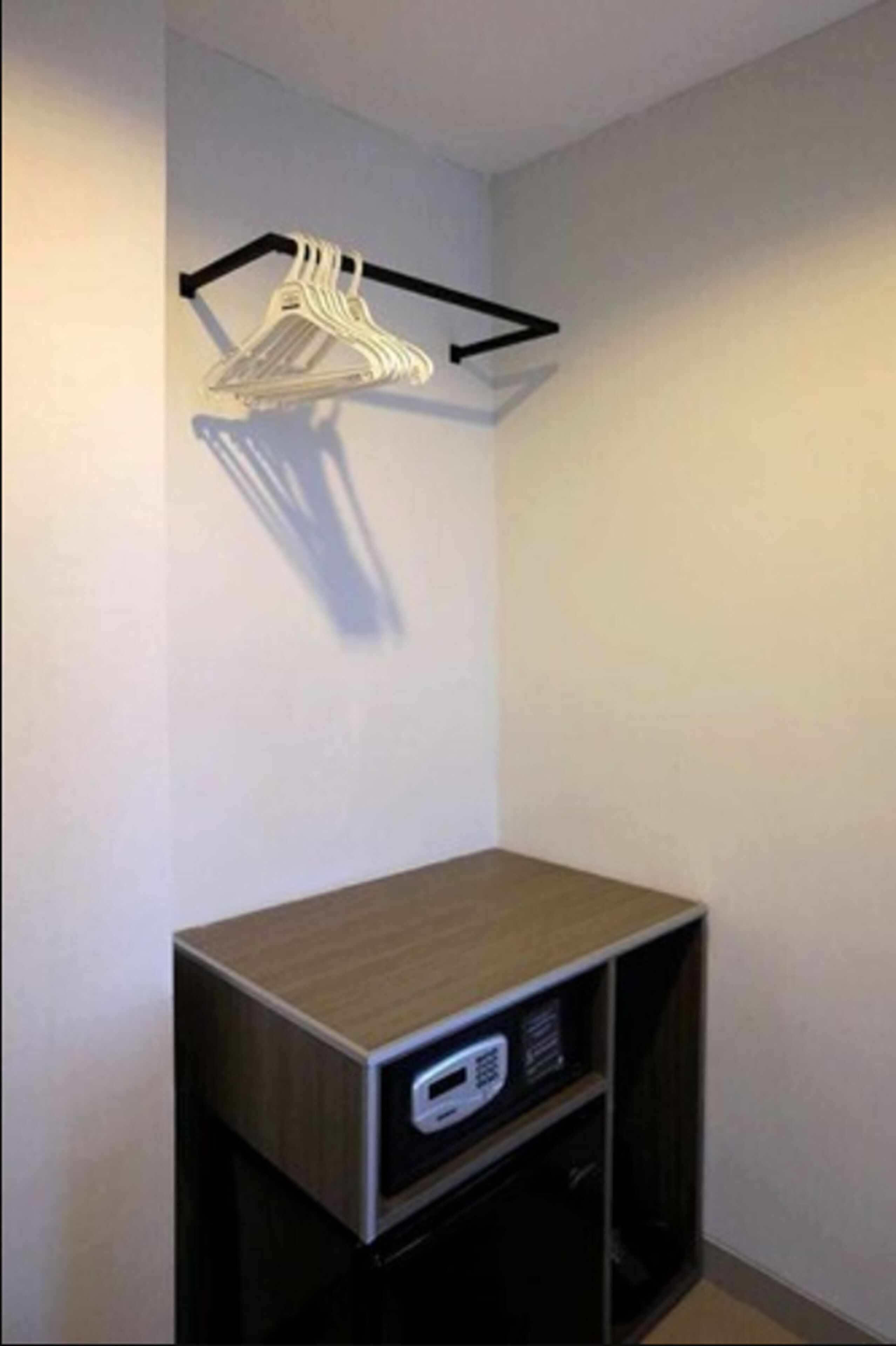 A corner room with a wooden cabinet and a black shelf unit.