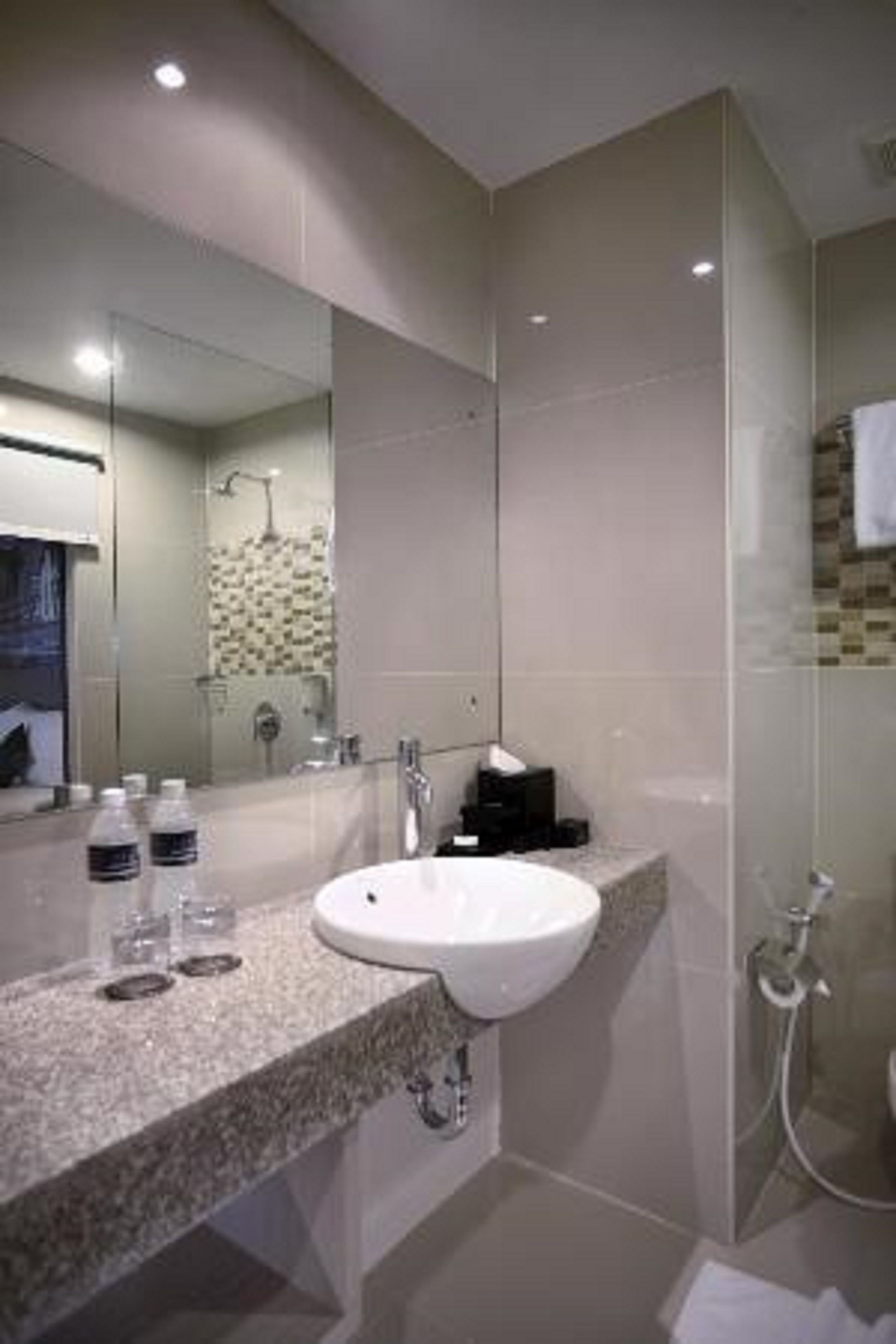 A modern bathroom with a granite countertop, a white sink, a mirror, and a shower area.