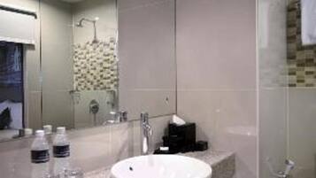 A modern bathroom with a granite countertop, a white sink, a mirror, and a shower area.