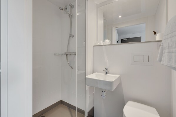 A modern bathroom with a glass shower enclosure, a white sink, and a toilet. - Balladins Blois (Blois)