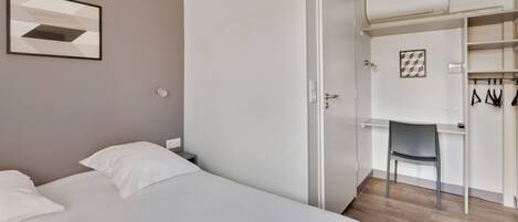Un dormitorio con cama, escritorio y silla.
