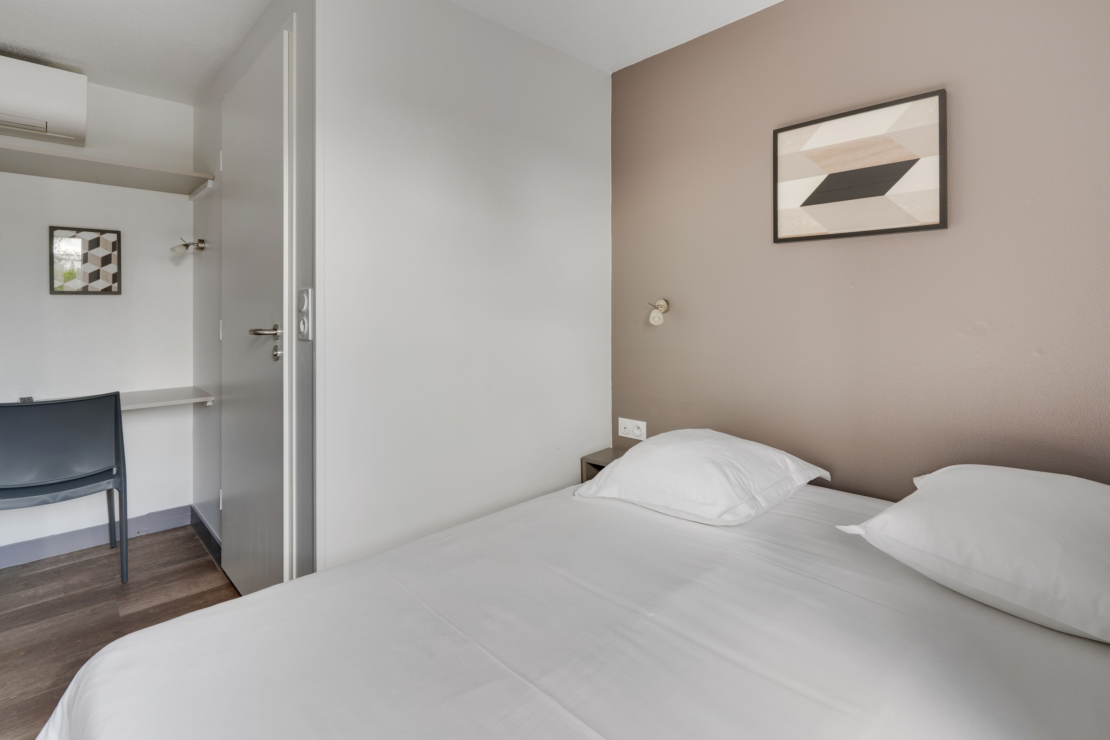 Une chambre d’hôtel avec un lit, un bureau et une chaise.