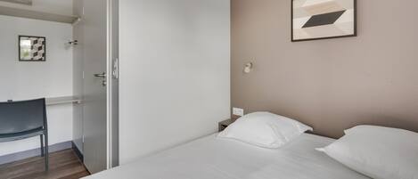 A hotel room with a bed, a desk, and a chair.