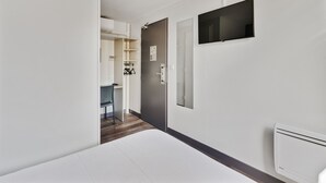 A modern hotel room with a large bed, a flat-screen TV mounted on the wall, and a door leading to a bathroom. - Balladins Blois (Blois)