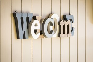 Een houten wand met het woord 'Welcome' in grote, opstaande letters.