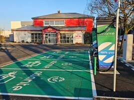 Zona de estacionamiento para bicicletas verdes con estación de carga para vehículos eléctricos.